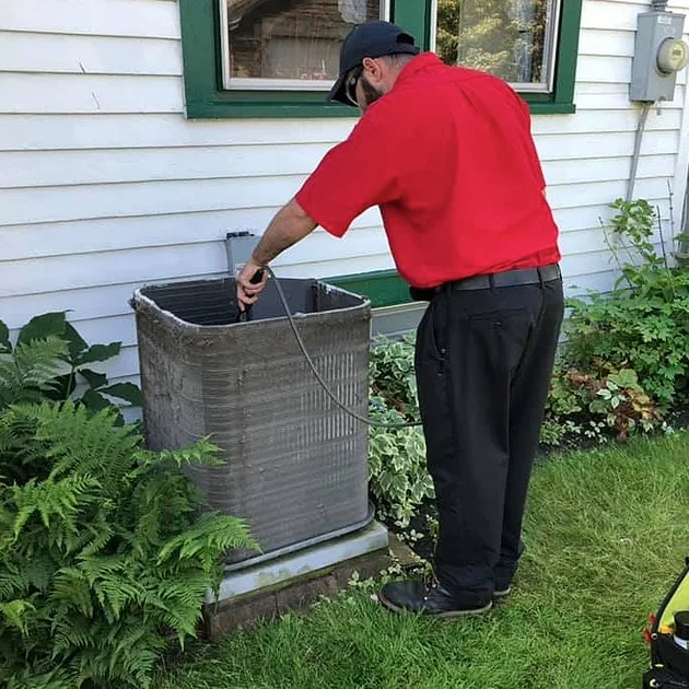 As part of our AC tune-up in Tonawanda, NY, our technician cleans out the inside of the AC condenser unit.