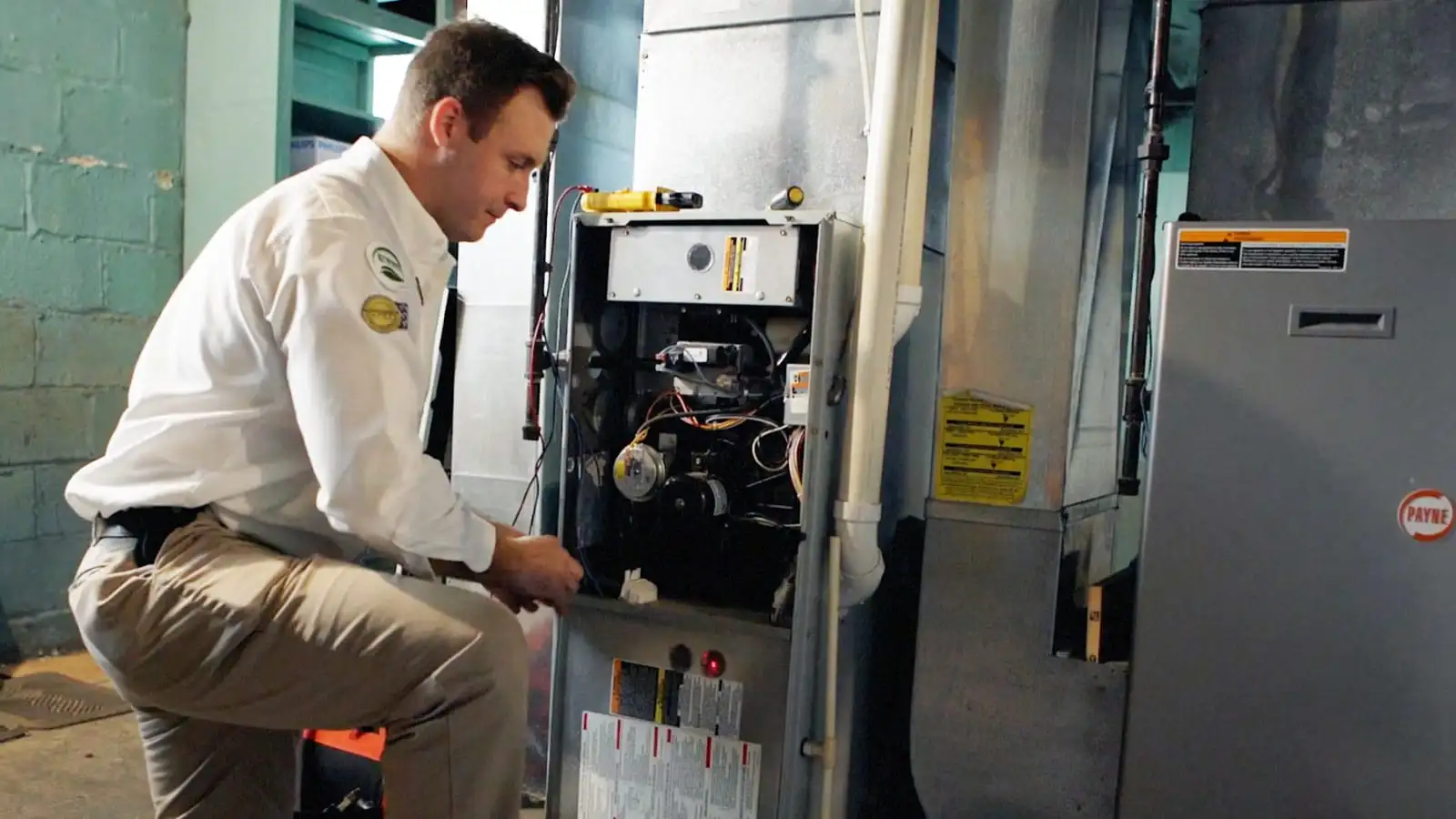 A Reimer technician kneels next to a furnace as they put the finishing touches on a new furnace install.