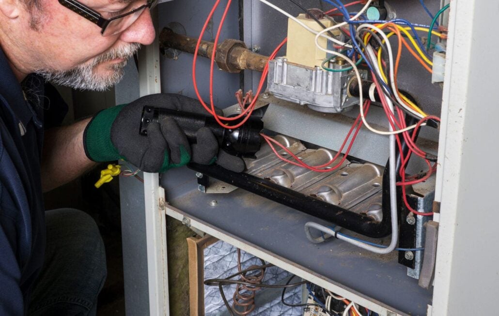 A Reimer technician uses a flashlight to look inside this gas furnace, inspecting it for any major issues ahead of winter.