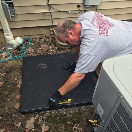 A Reimer technician ensures that the AC concrete pad is completely level before moving forward with installation.