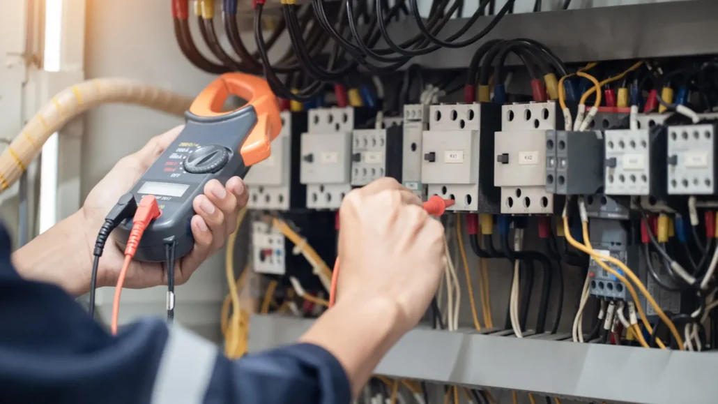 A technician on an emergency callout inspecting an electrical panel or faulty wiring with an electrical tester.