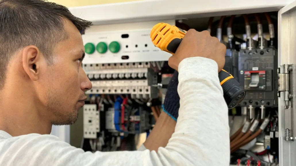 An electrician safely installing or replacing wiring inside a residential electrical panel